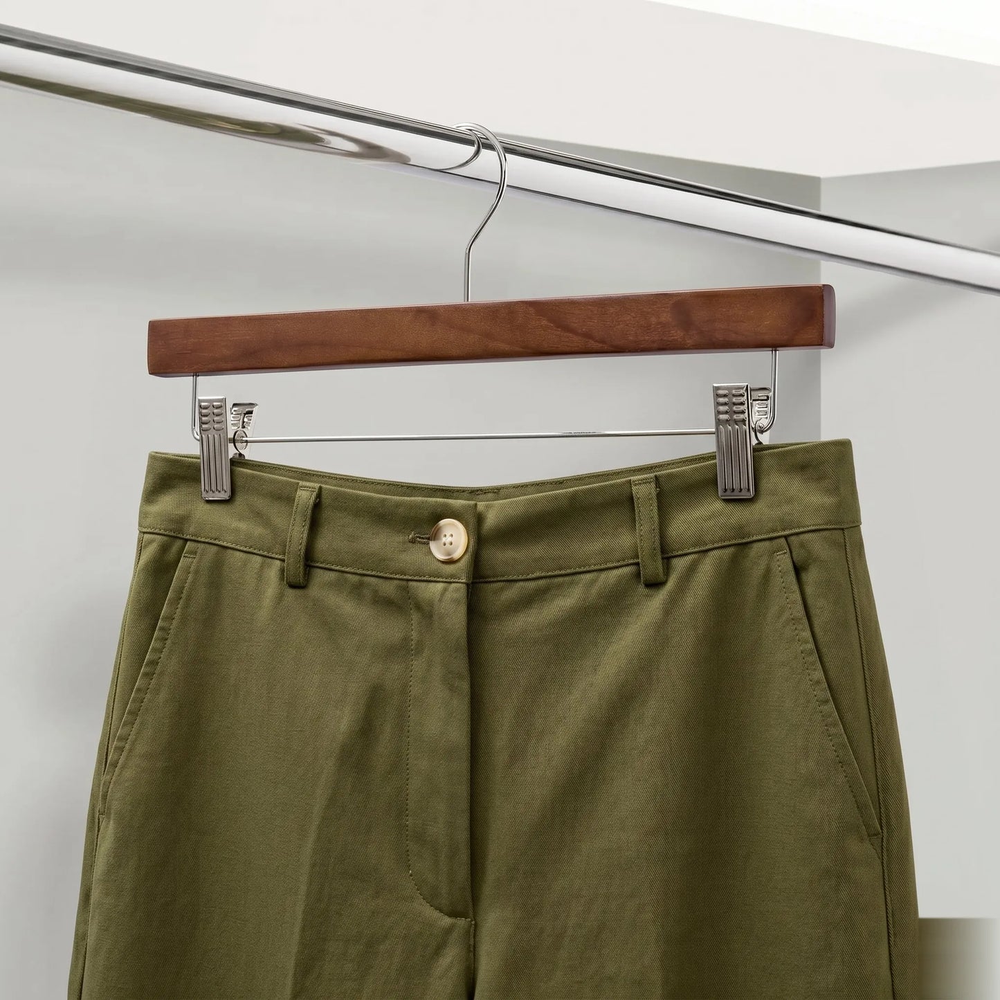 Green pants on a wooden hanger against a white background