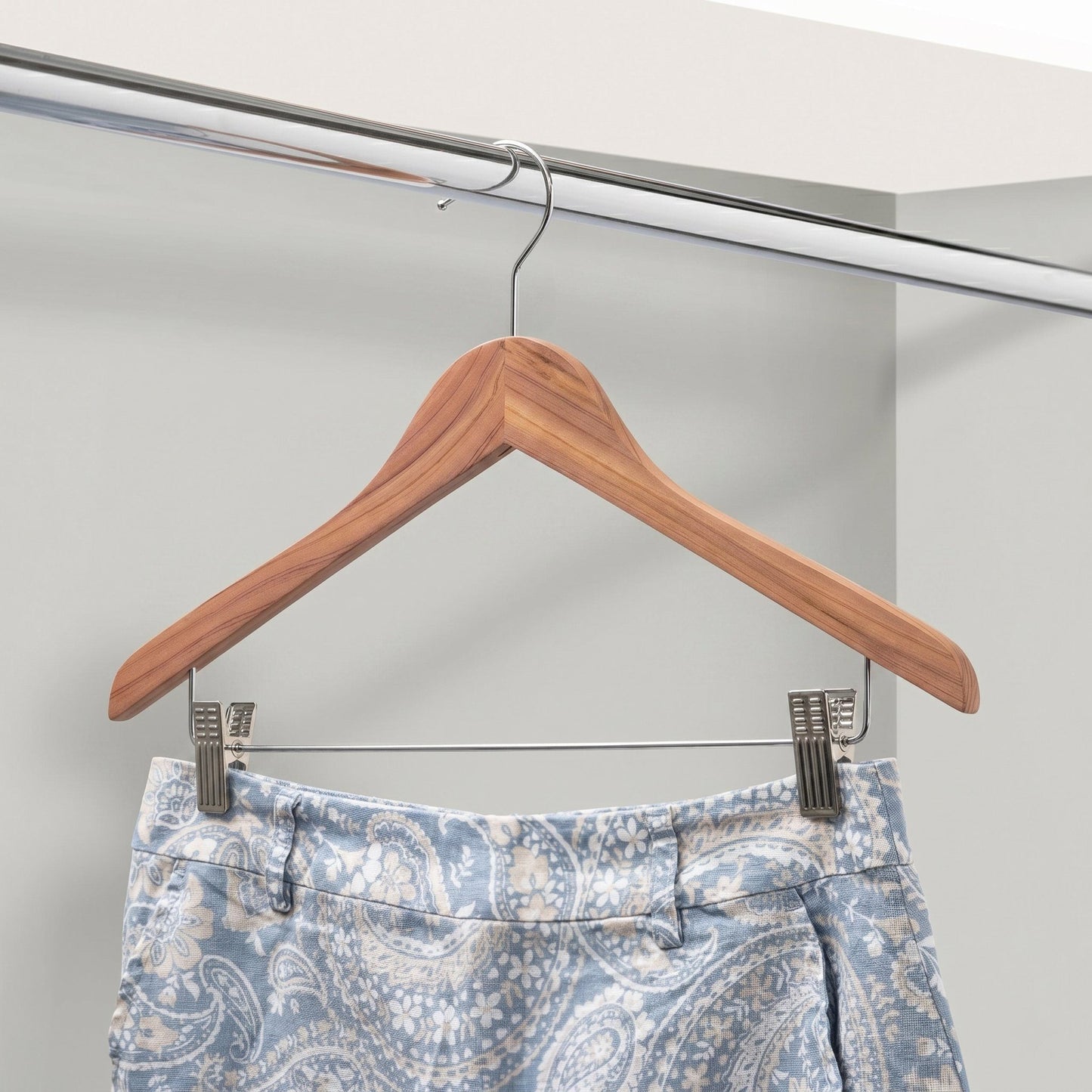 Cedar Wooden hanger with a pair of blue patterned pants on a white background