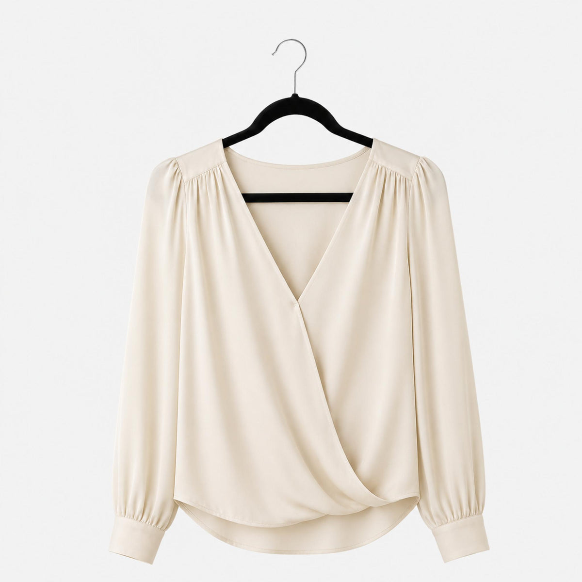 Beige blouse on a hanger against a white background
