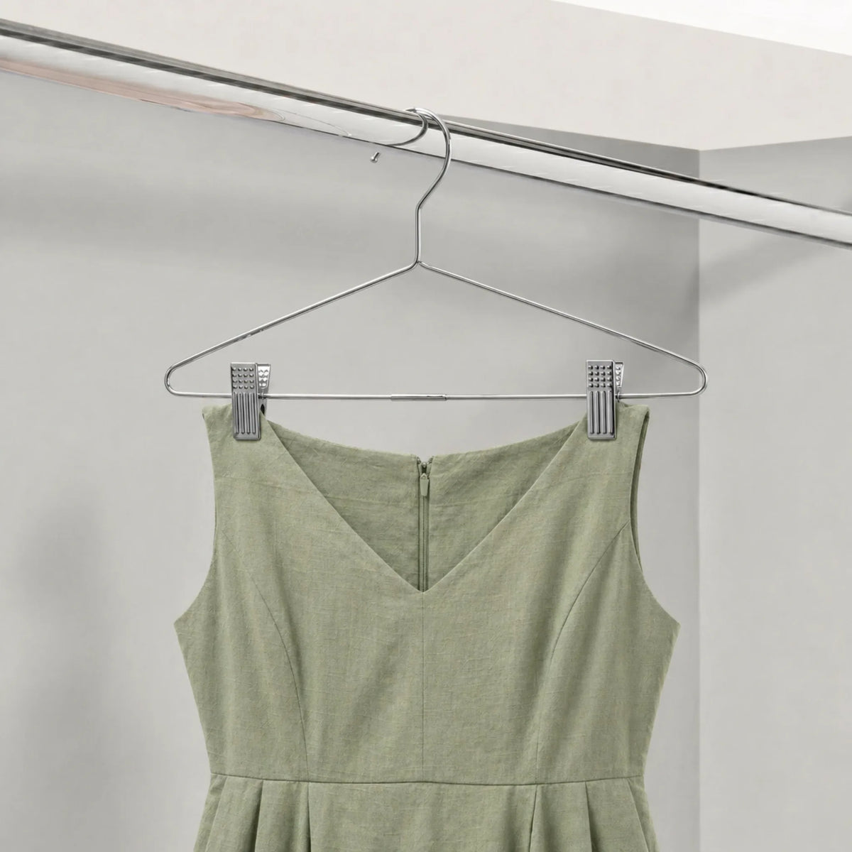 Green dress hanging on a metal hanger against a white background
