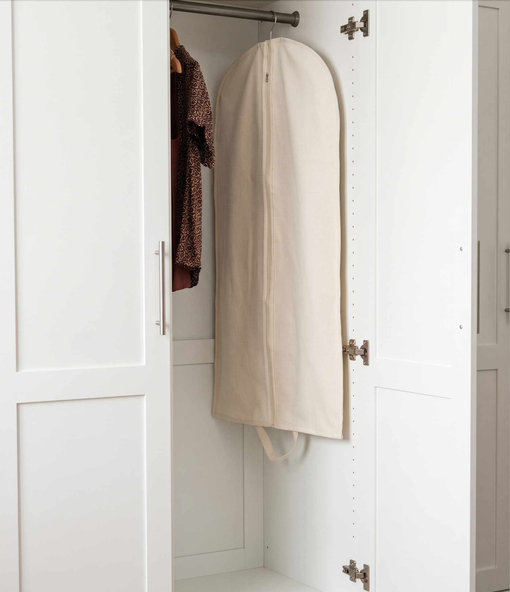 White garment bag hanging inside a white wardrobe
