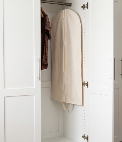 White garment bag hanging inside a white wardrobe