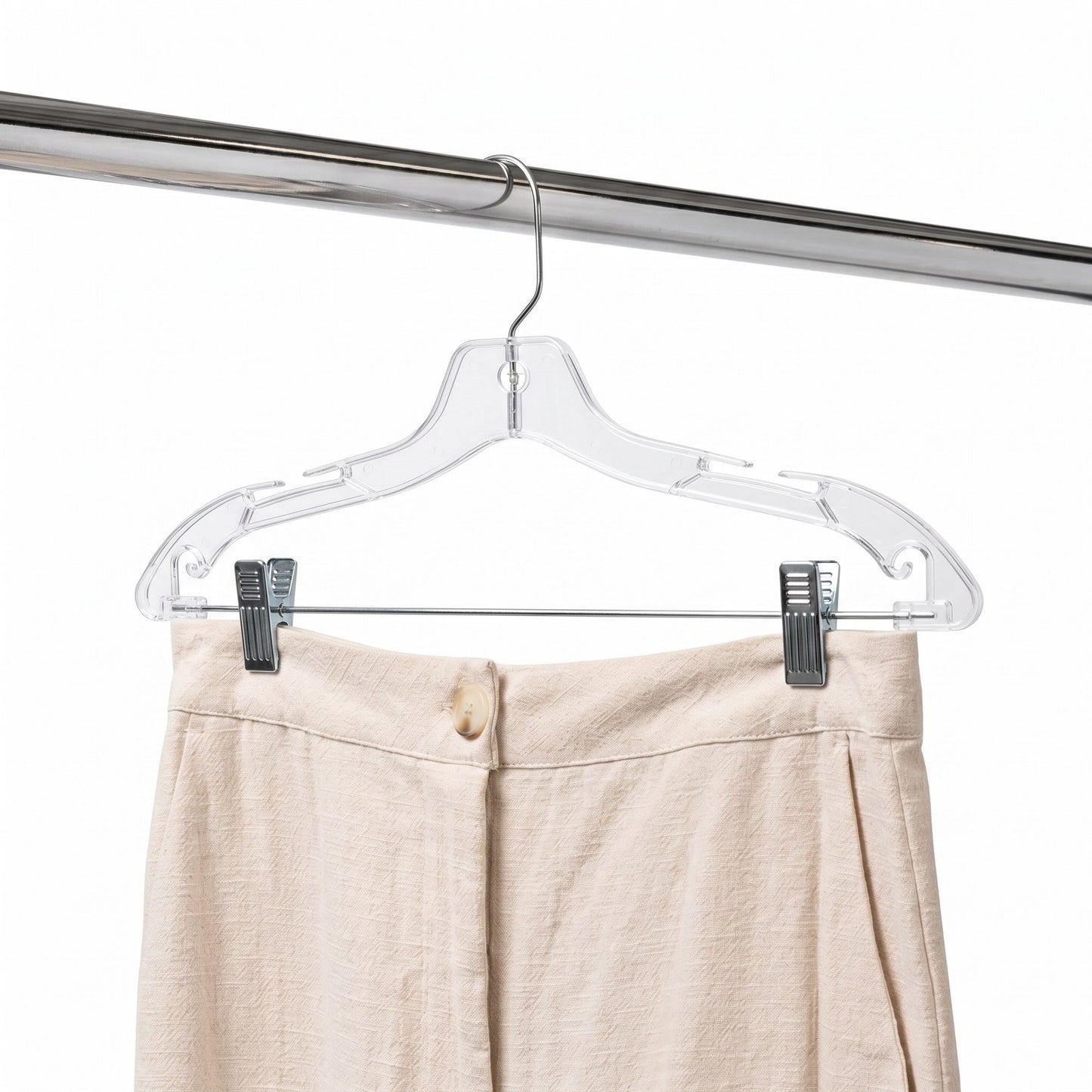 Clear plastic hanger with beige pants on a white background