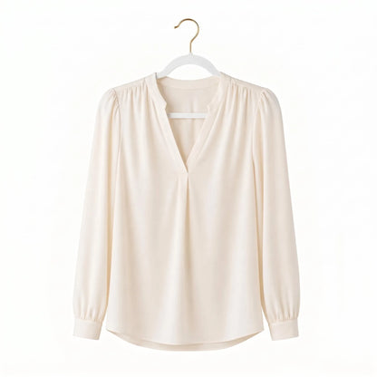 Beige blouse on a hanger against a white background
