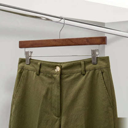 Green pants on a wooden hanger against a white background