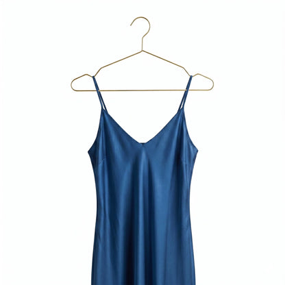 Blue slip dress on a gold hanger against a white background