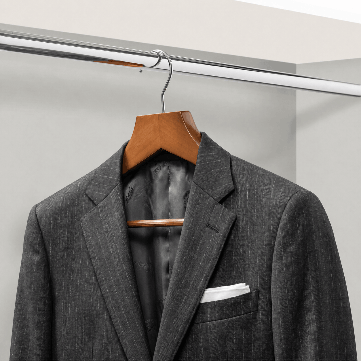 Gray suit jacket on a wooden hanger against a white background