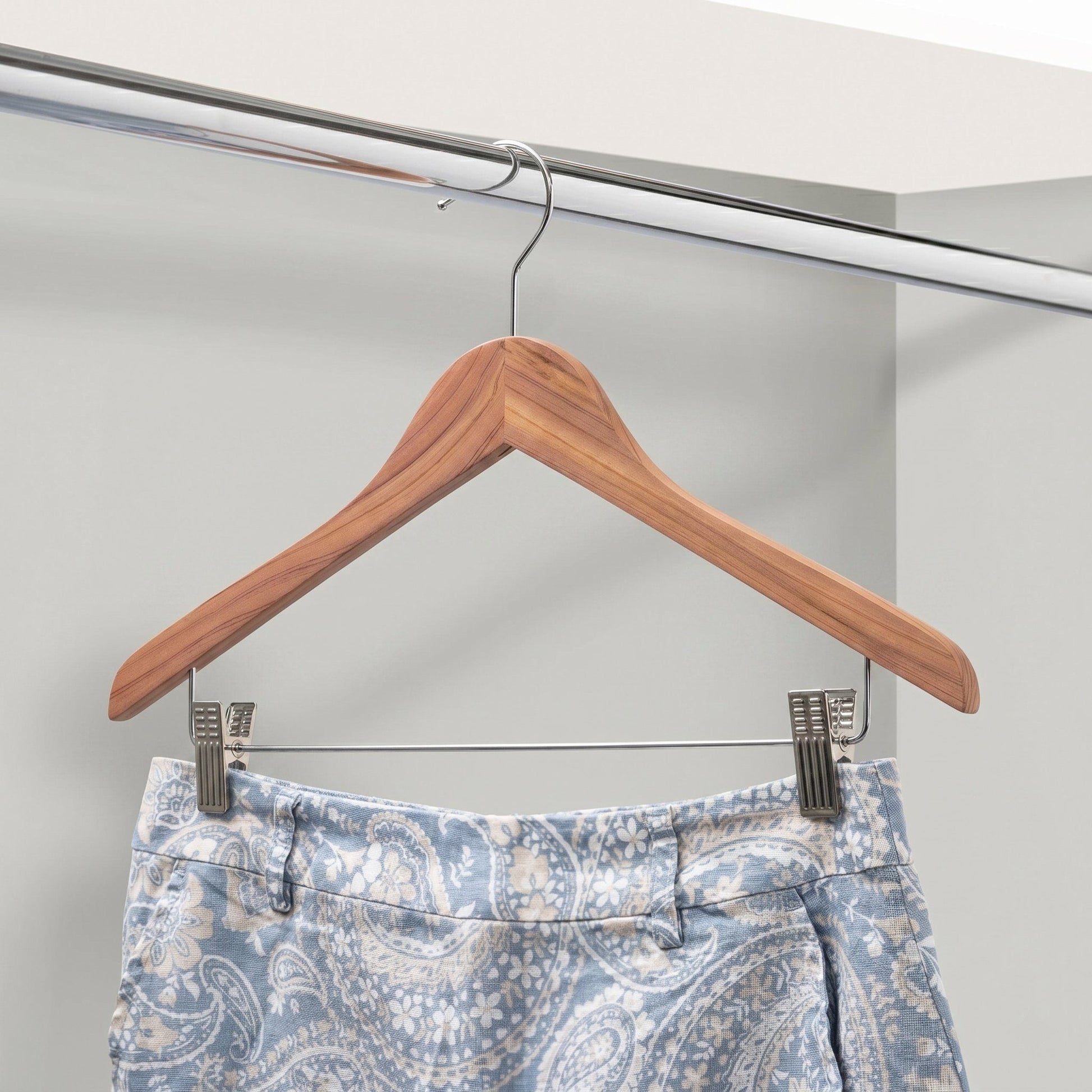 Cedar Wooden hanger with a pair of blue patterned pants on a white background
