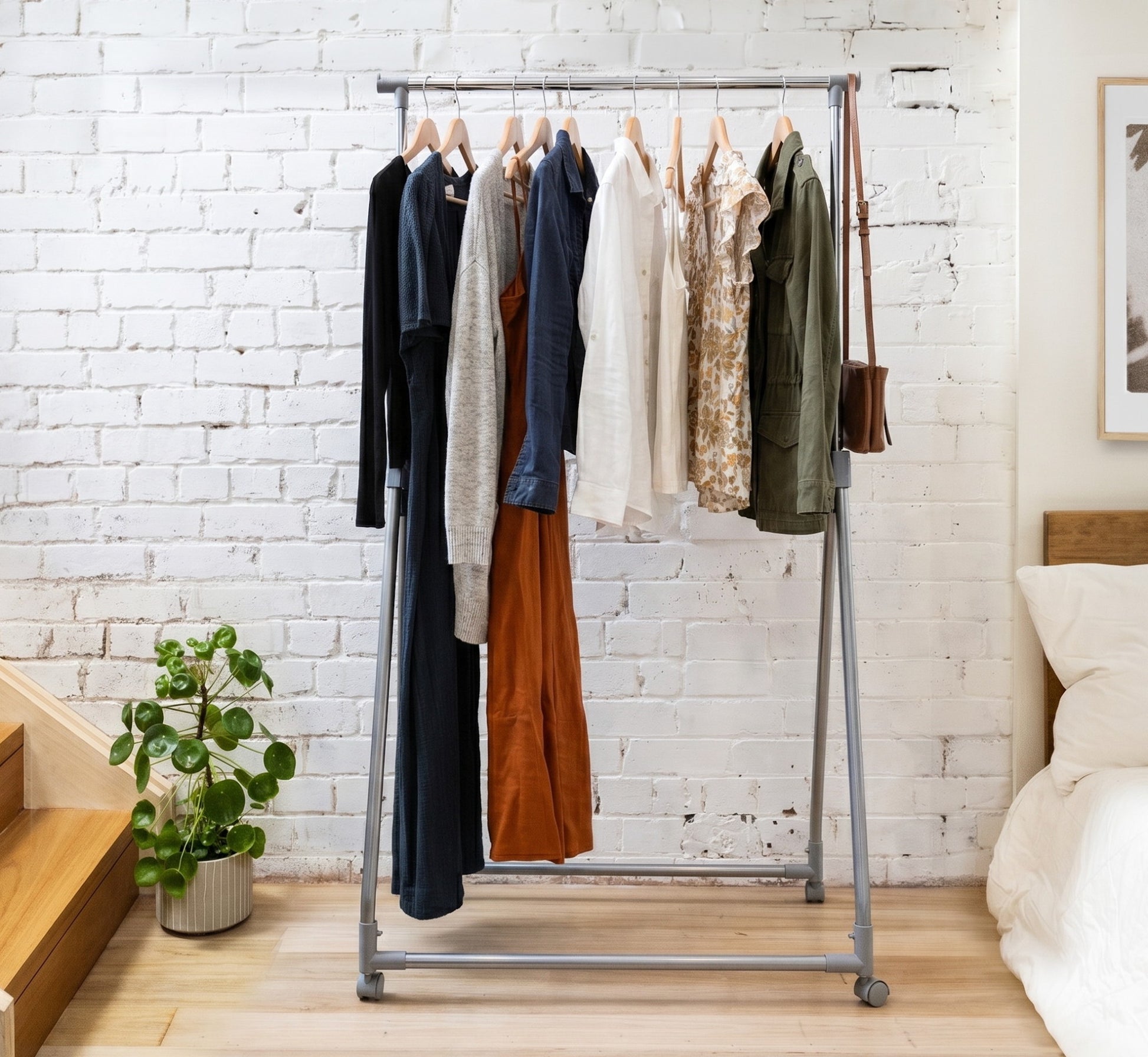 Clothing rack with clothes against a white brick wall in a room.