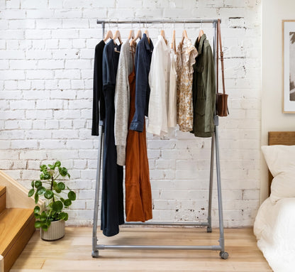 Clothing rack with clothes against a white brick wall in a room.