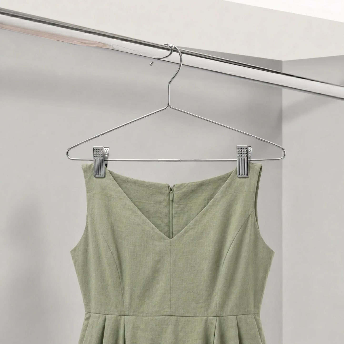 Green dress hanging on a metal hanger against a white background