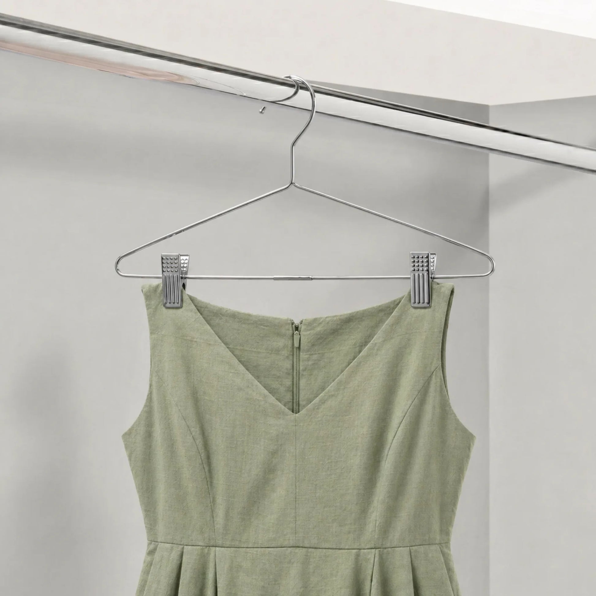 Green dress hanging on a metal hanger against a white background