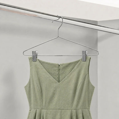 Green dress hanging on a metal hanger against a white background
