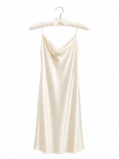 Cream-colored satin slip dress on a hanger against a white background